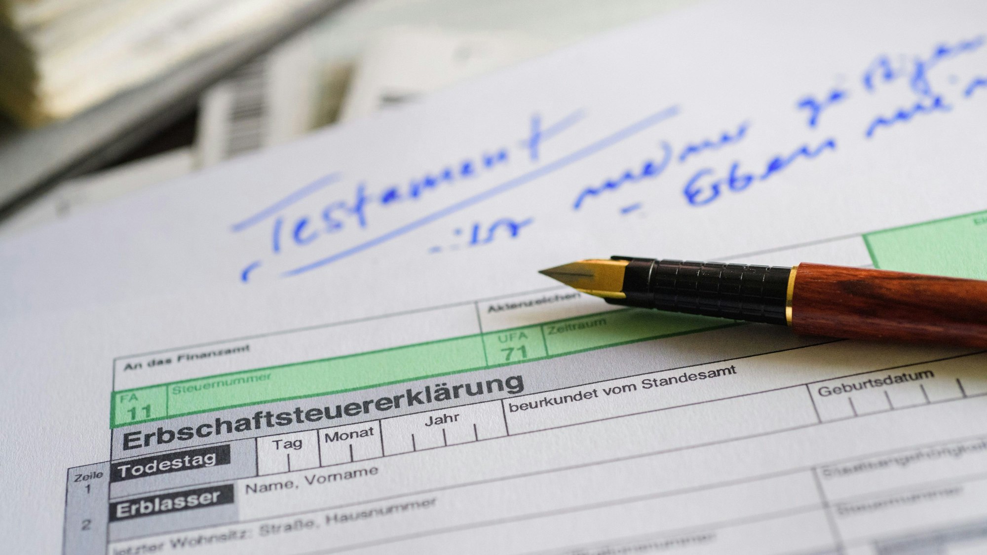 ARCHIV - 10.04.2017, Berlin: ILLUSTRATION - Ein Formular für die Erbschaftsteuererklärung sowie Stift und Testament liegen in Berlin auf einem Tisch.