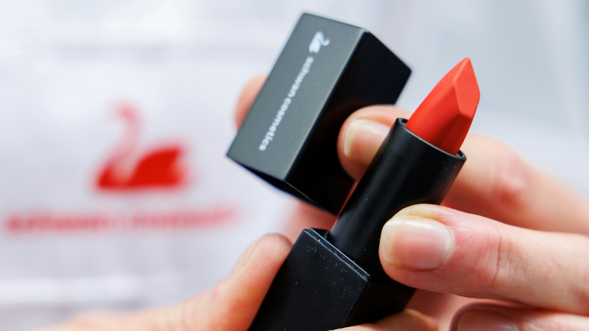 Eine Mitarbeiterin von Schwan Cosmetics, dem Geschäftsfeld Kosmetik der Schwanhäußer Industrie Holding GmbH & Co.KG, hält einen Lippenstift aus der Produktion des Unternehmens in der Hand.