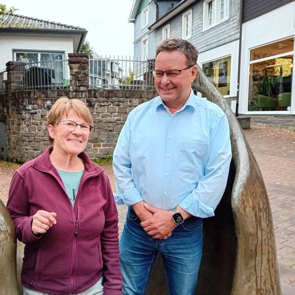 Eine Frau und ein Mann an zwei Bronze-Figuren.