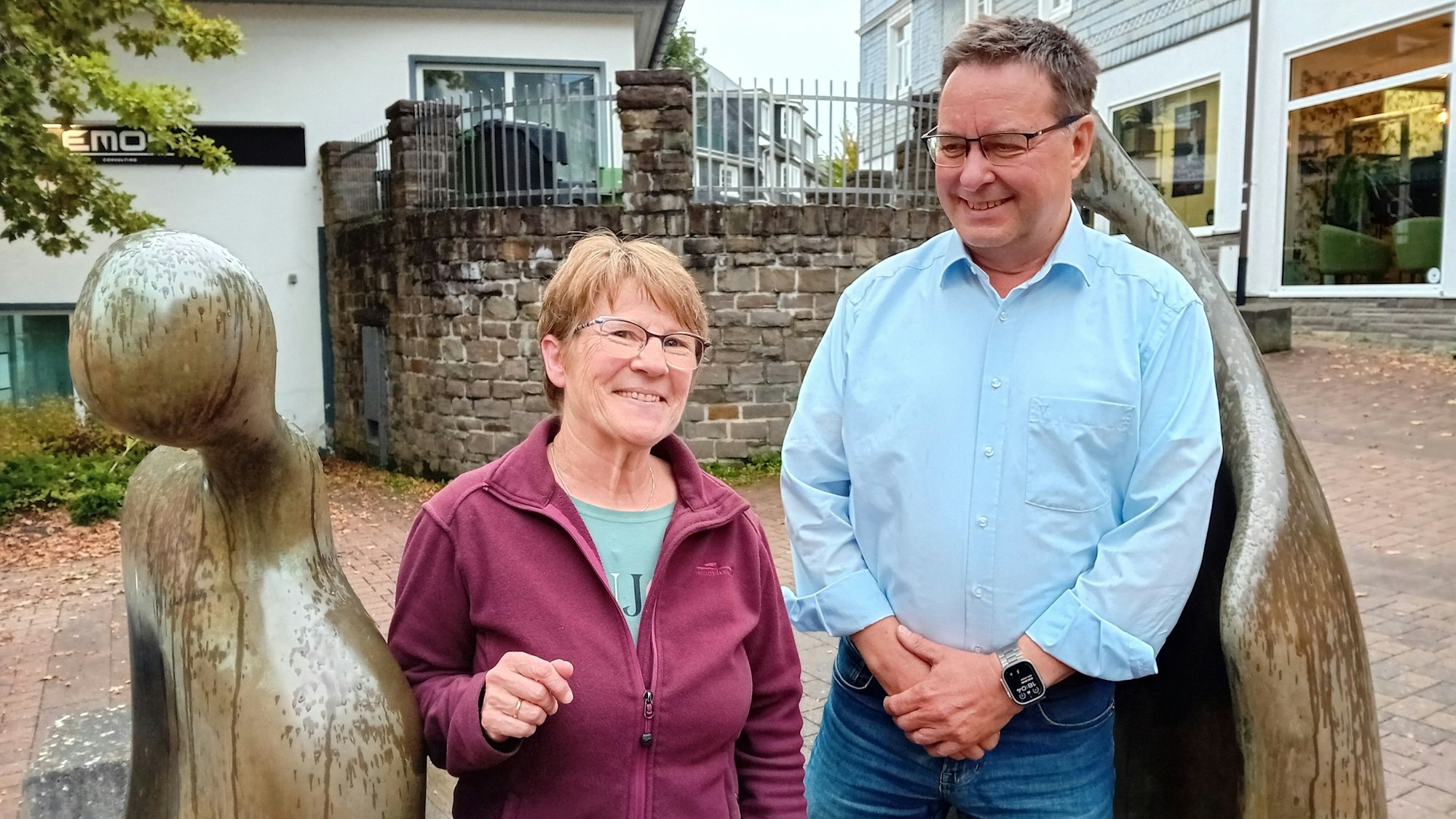 Eine Frau und ein Mann an zwei Bronze-Figuren.