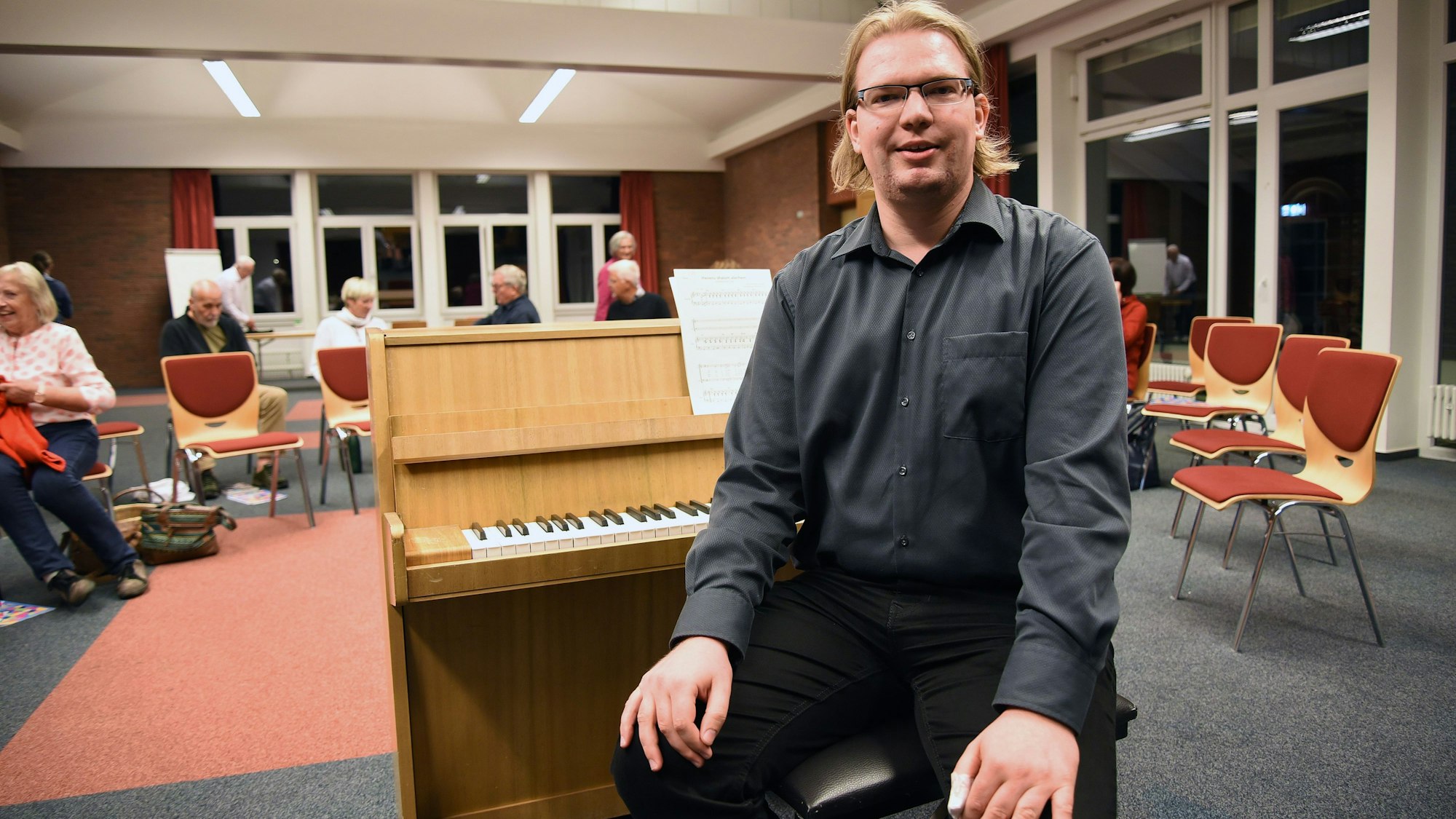 Das Foto zeigt Chorleiter Samuel Schmidt mit einem Klavier.