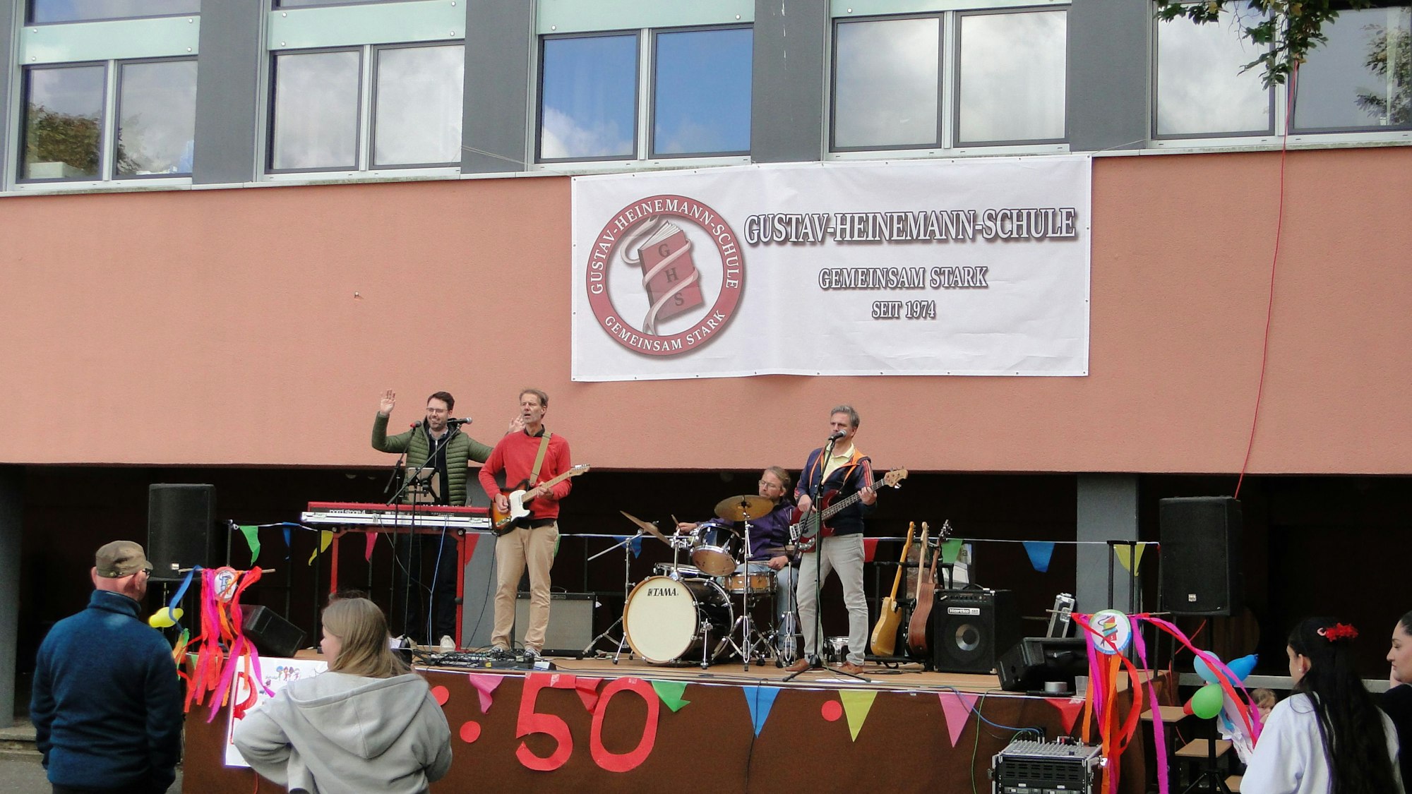 Mit „Gigi Homerecording“ trat auch eine Band des Lehrerkollegiums auf. Das neue Logo auf dem Transparent wurde beim Fest zum ersten Mal enthüllt.