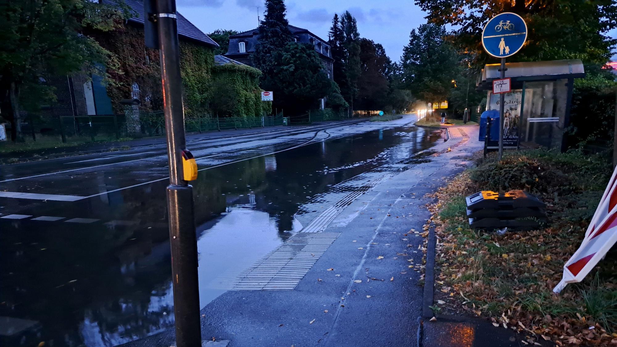 Eine vollgelaufene Straße vor einer Bushaltestelle.