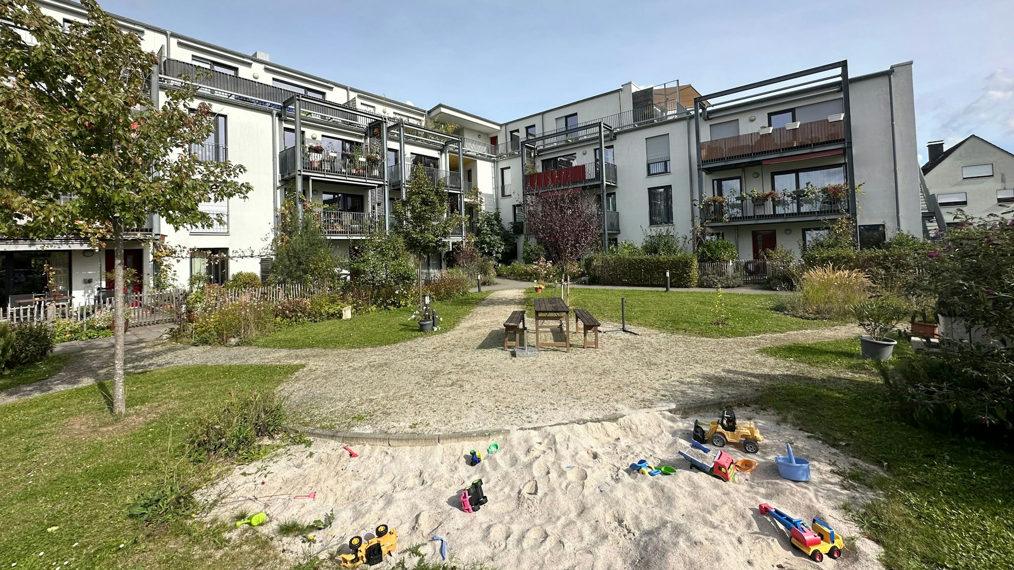 Blick in den Innenhof des Gebäudes in L-Form mit einem Spielplatz.