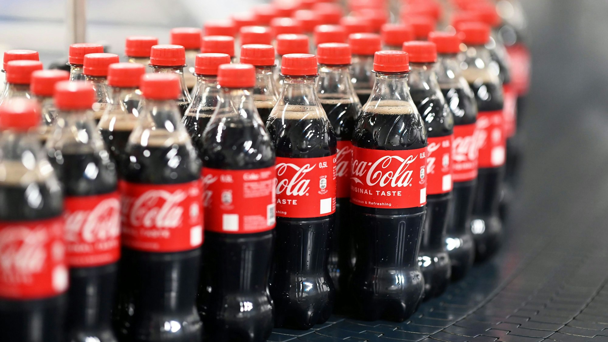 Am Produktionsstandort Mannheim von Coca-Cola Europacific Partners - CCEP Deutschland GmbH werden abgefüllte 0,5 Liter Einweg Coca-Cola Flaschen über ein Förderband transportiert.