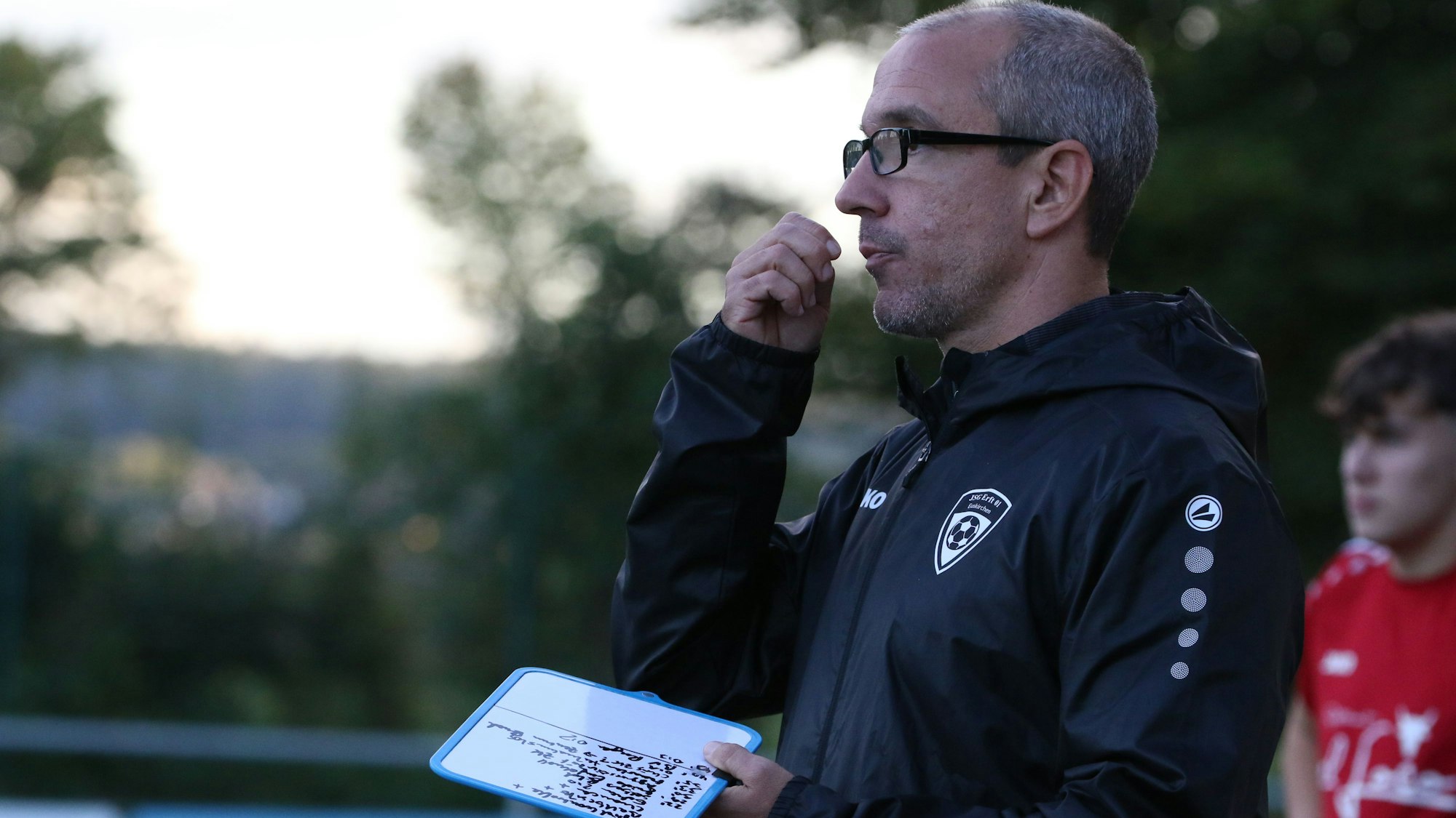 Das Bild zeigt Thomas Perschmann an der Seitenlinie. In der linken Hand hält er einen Notizblock.