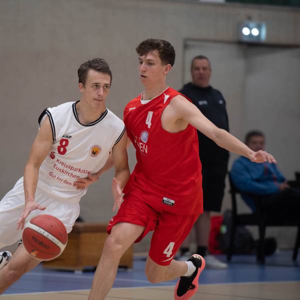 Ein Basketballer des TuS Zülpich im weißen Trikot dribbelt den Ball an seinem Kontrahenten von den Erftbaskets vorbei.