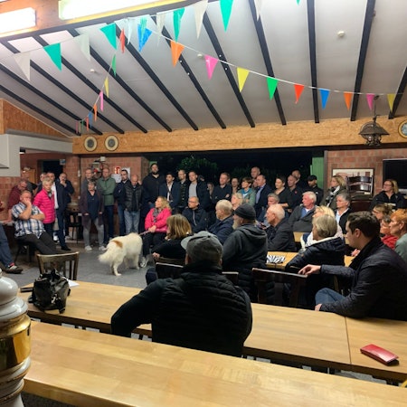 Das Bild zeigt eine Menschentraube, die sich bei einer Versammlung im Schützenhaus Königsdorf gebildet hat.