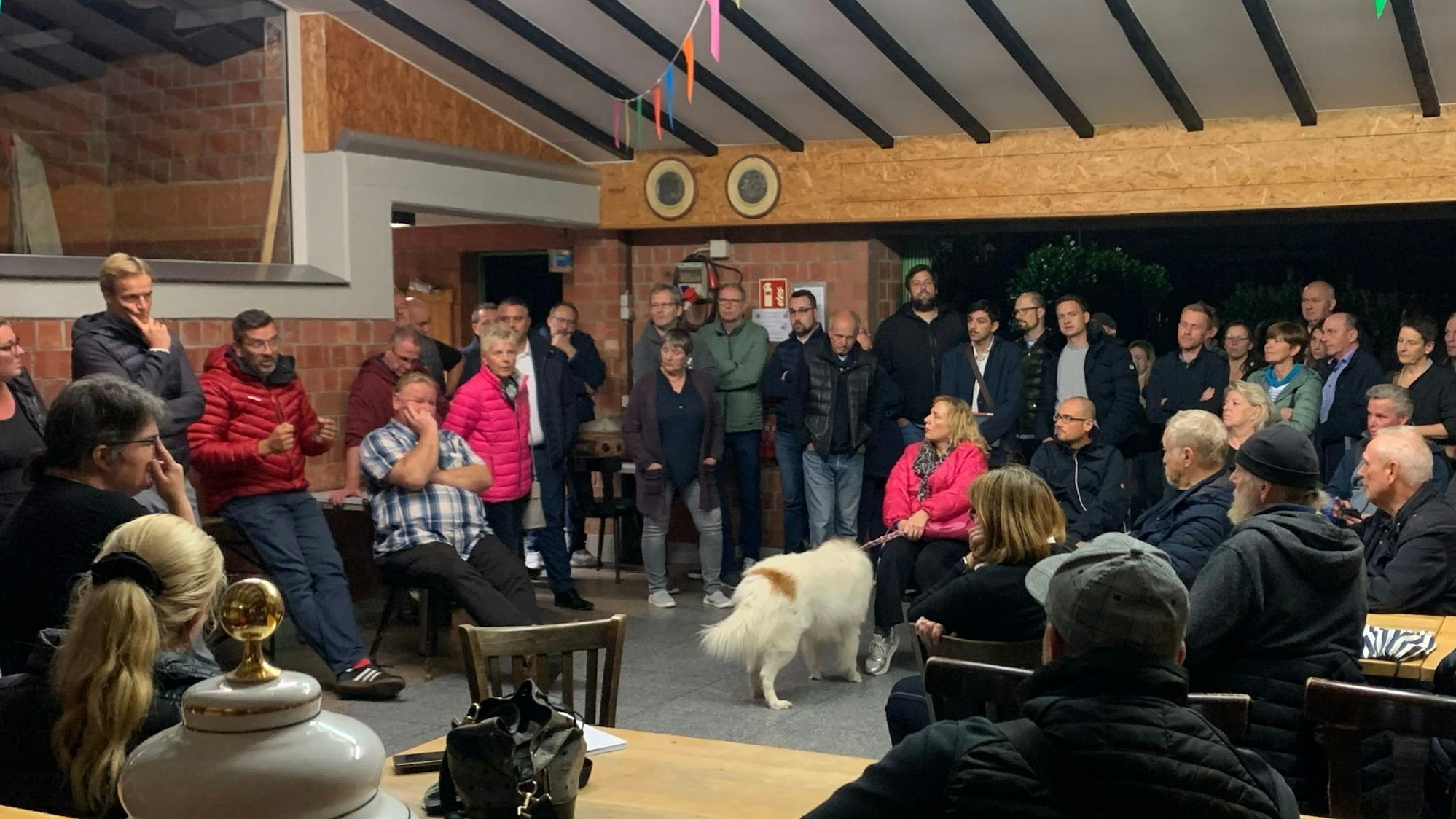 Das Bild zeigt eine Menschentraube, die sich bei einer Versammlung im Schützenhaus Königsdorf gebildet hat.