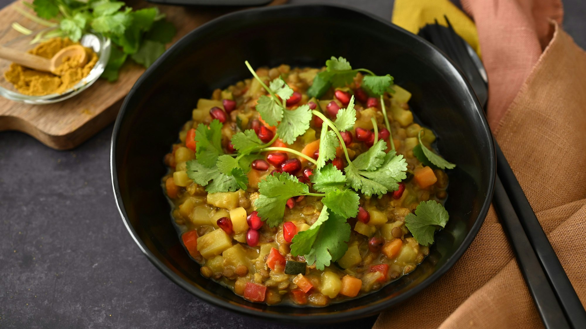 Frische Korianderblätter und Granatapfelkerne sind als Topping über den Linseneintopf gestreut.