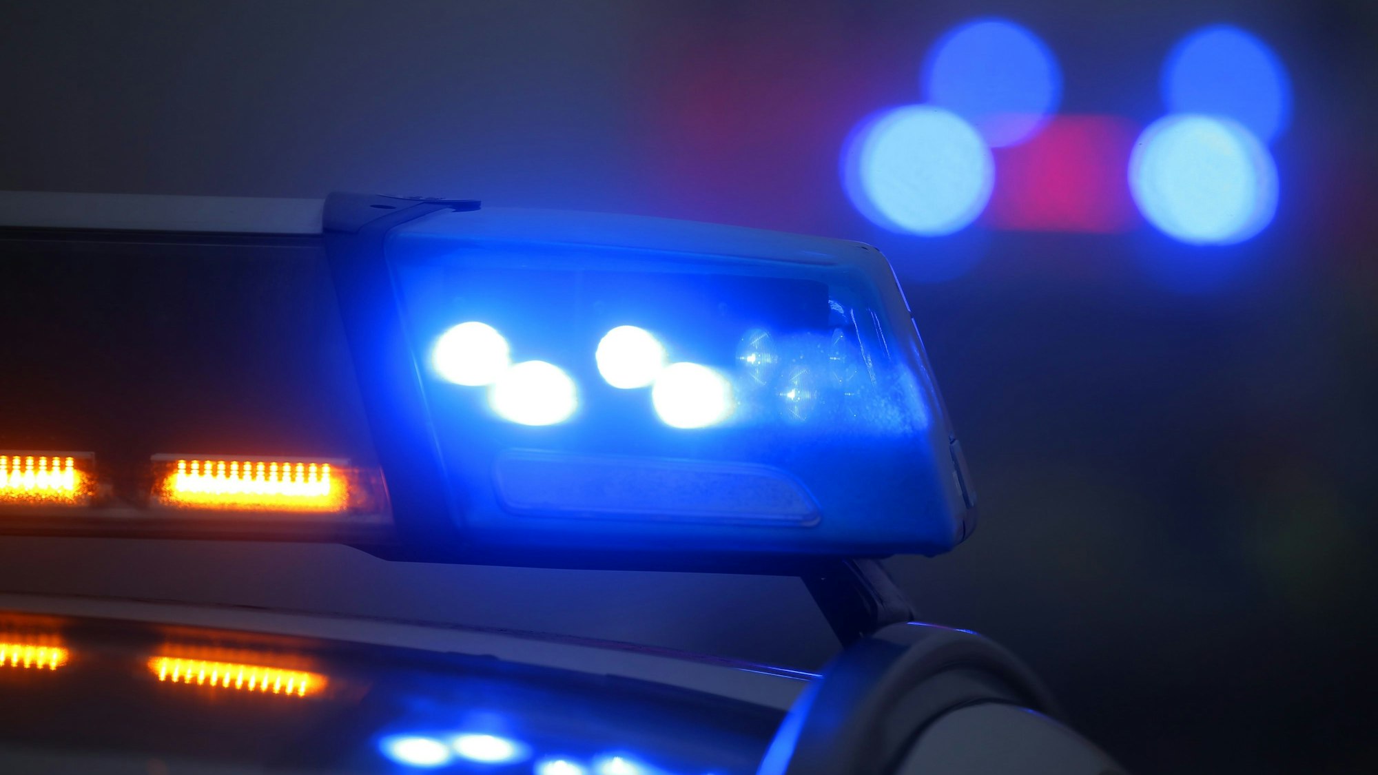 Ein Polizeiauto mit eingeschaltetem Blaulicht steht an einer Unfallstelle.
