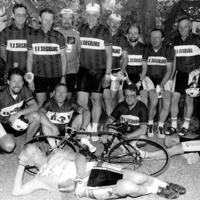 Ein schwarz-weiß-Foto von Männern in Trikots und einem Fahrrad.