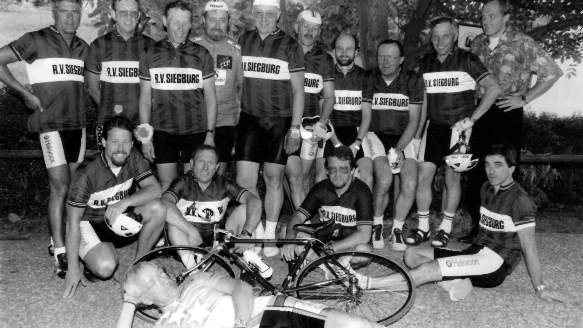 Ein schwarz-weiß-Foto von Männern in Trikots und einem Fahrrad.