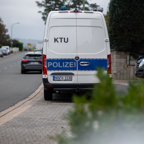 An einer Straße in Zülpich-Füssenich steht ein Kastenwagen der Polizei, auf dem die Aufschrift „KTU“ zu sehen ist.