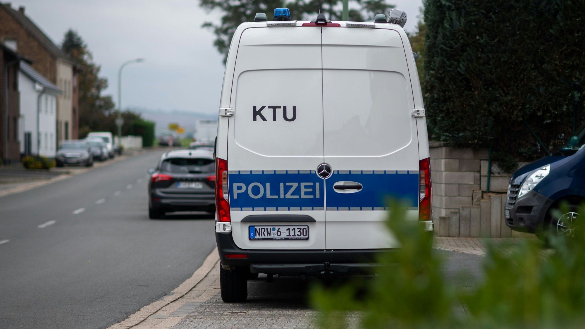 An einer Straße in Zülpich-Füssenich steht ein Kastenwagen der Polizei, auf dem die Aufschrift „KTU“ zu sehen ist.