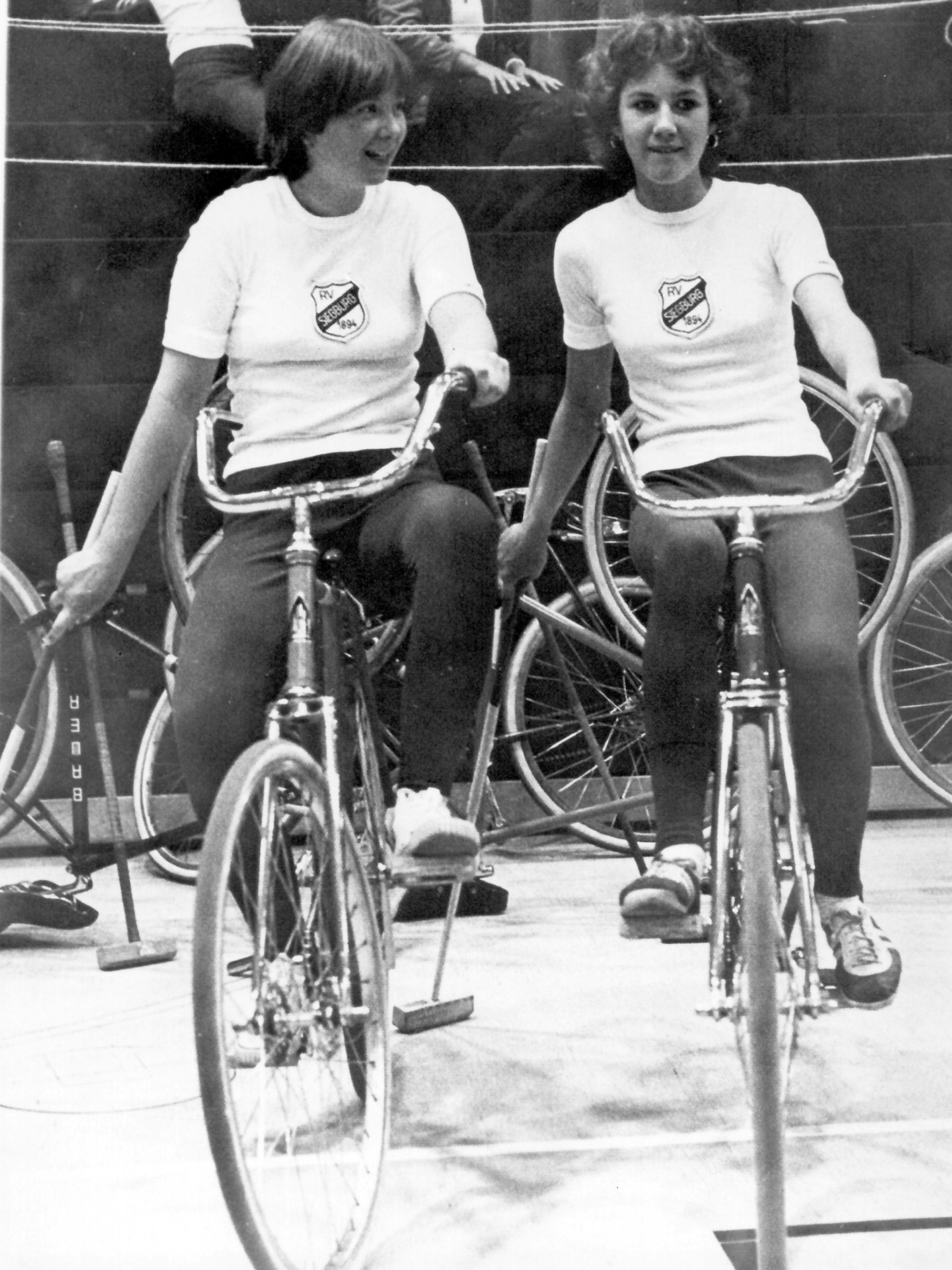 Ein schwarz-weiß-Foto von zwei jungen Frauen auf Fahrrädern.