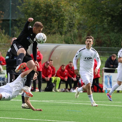 Einen spektakulären Zweikampf liefern sich Niclas Hampel im schwarzen Trikot und Marlon Große. Der Niefelder Spieler springt über seinen Zülpicher Kontrahenten.