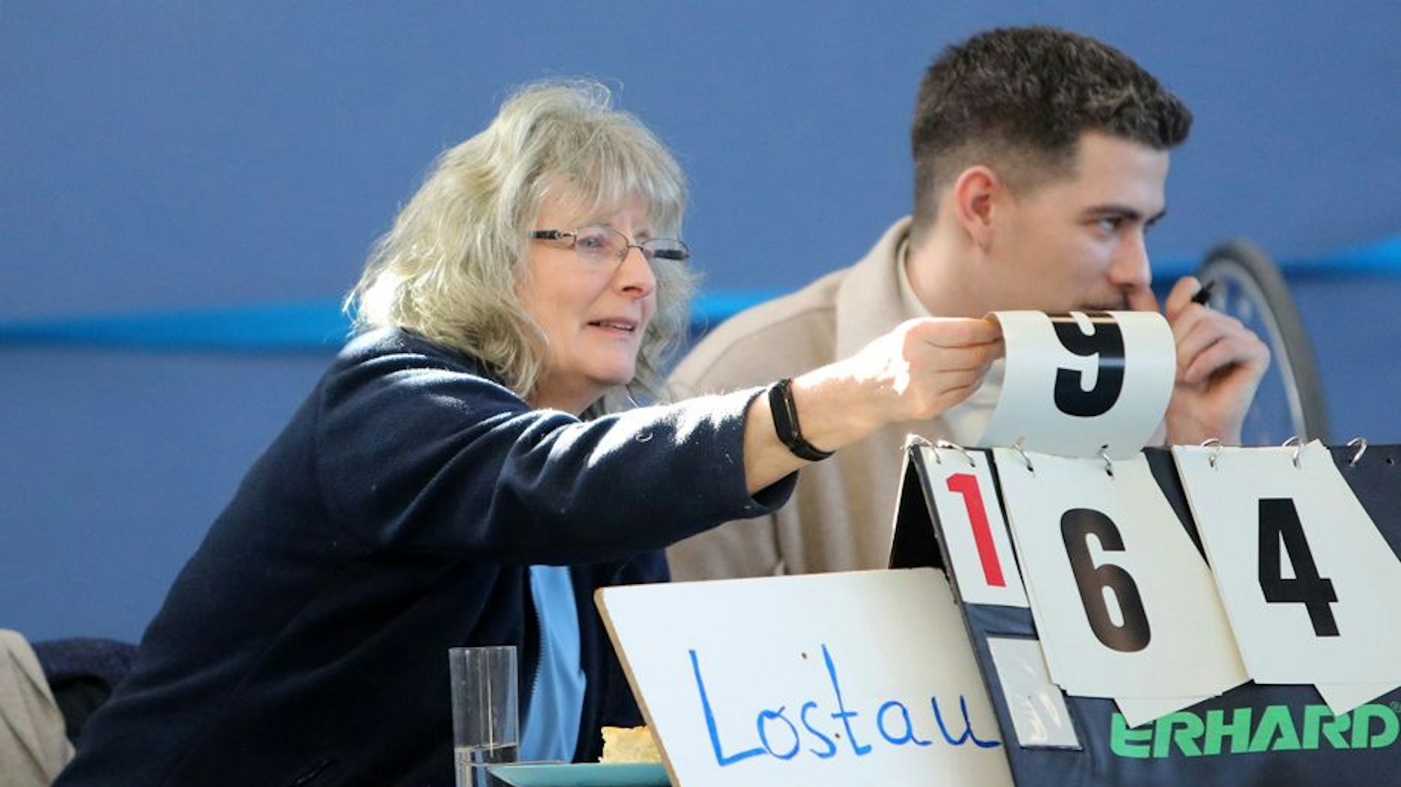 Eine blonde Frau dreht Nummer auf einer Tafel um.