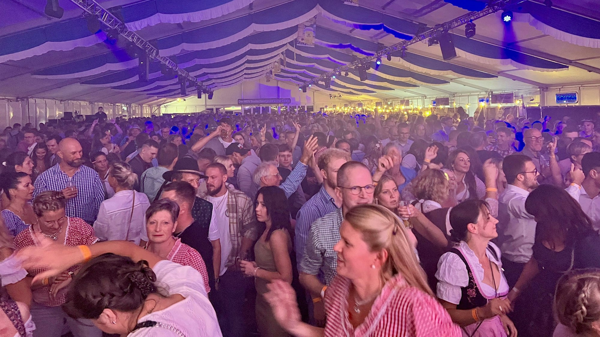Menschen feiern in einem vollen Festzelt.