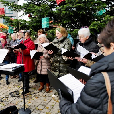 Ein Chor singt am ersten Adventswochenende 2023 vor einem großen Weihnachtsbaum beim Adventsmarkt auf dem Mondorfer Adenauerplatz.