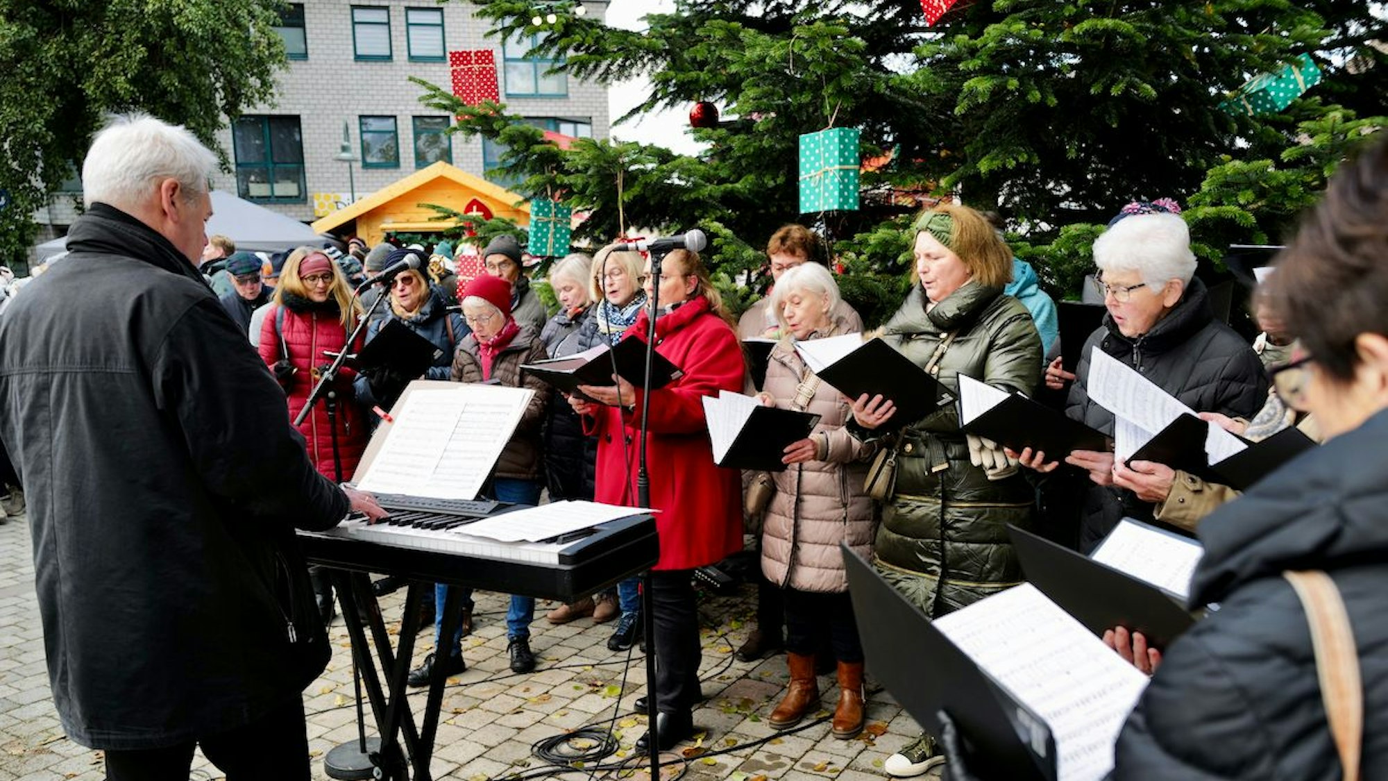 Ein Chor singt am ersten Adventswochenende 2023 vor einem großen Weihnachtsbaum beim Adventsmarkt auf dem Mondorfer Adenauerplatz.