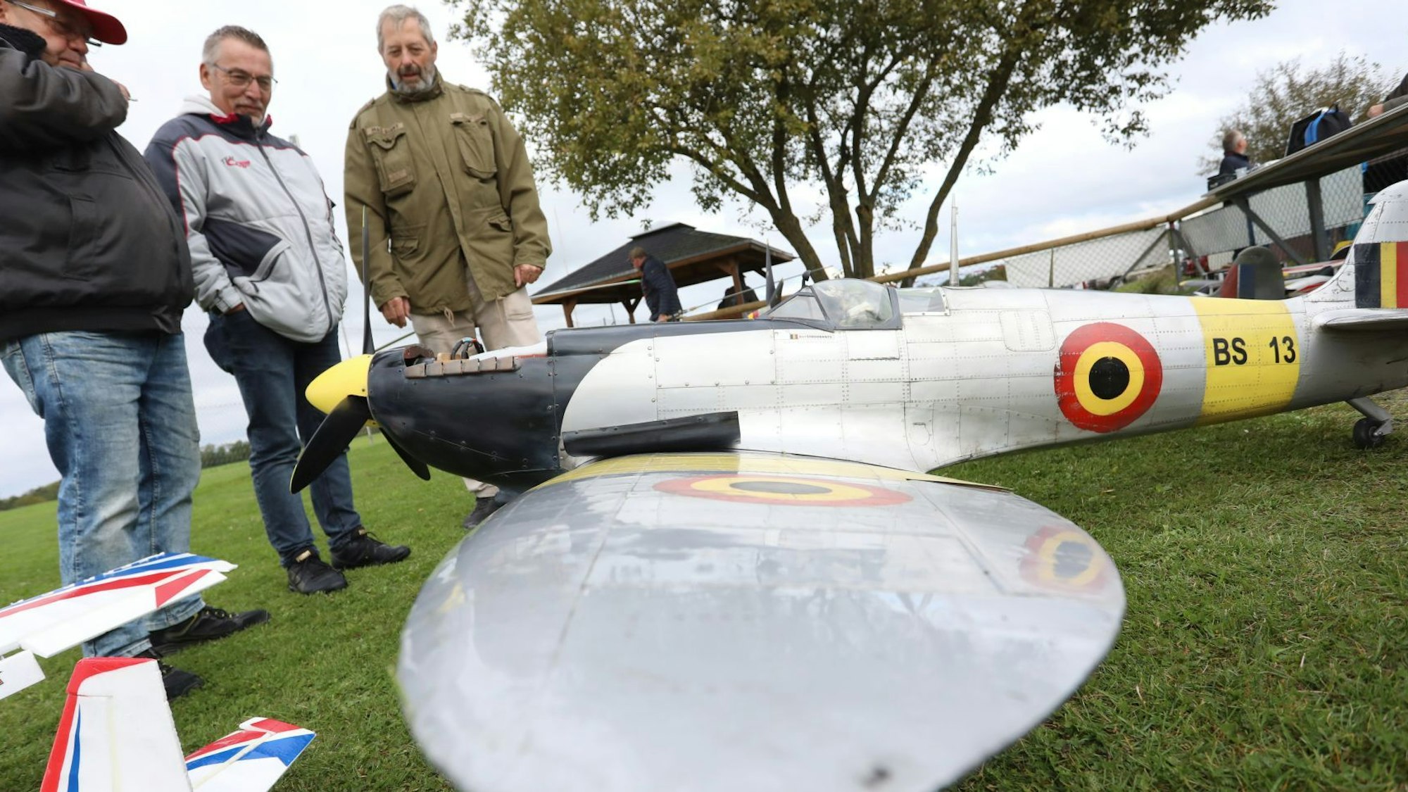 Drei Männer betrachten ein großes Flugzeugmodell.