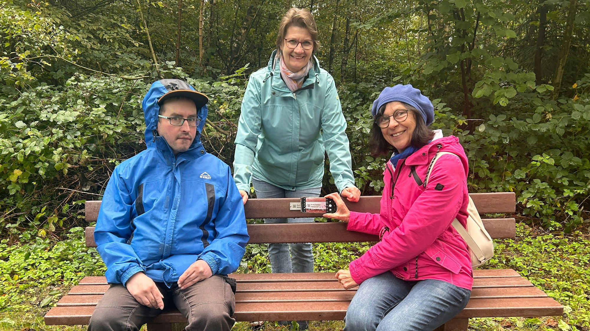 Rudi Voigt aus Burscheids Beirat für Inklusion, Gabriele Schumacher aus der Stadtverwaltung und die Vorsitzende des Beirats, Anne Stegert, auf einer Bank an der Balkantrasse