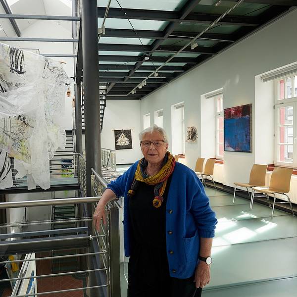 Kuratorin Eva-Maria Hermanns steht im Kunstforum in Gemünd an einer Arbeit von Helga Mols, die im Treppenaufgang installiert ist.