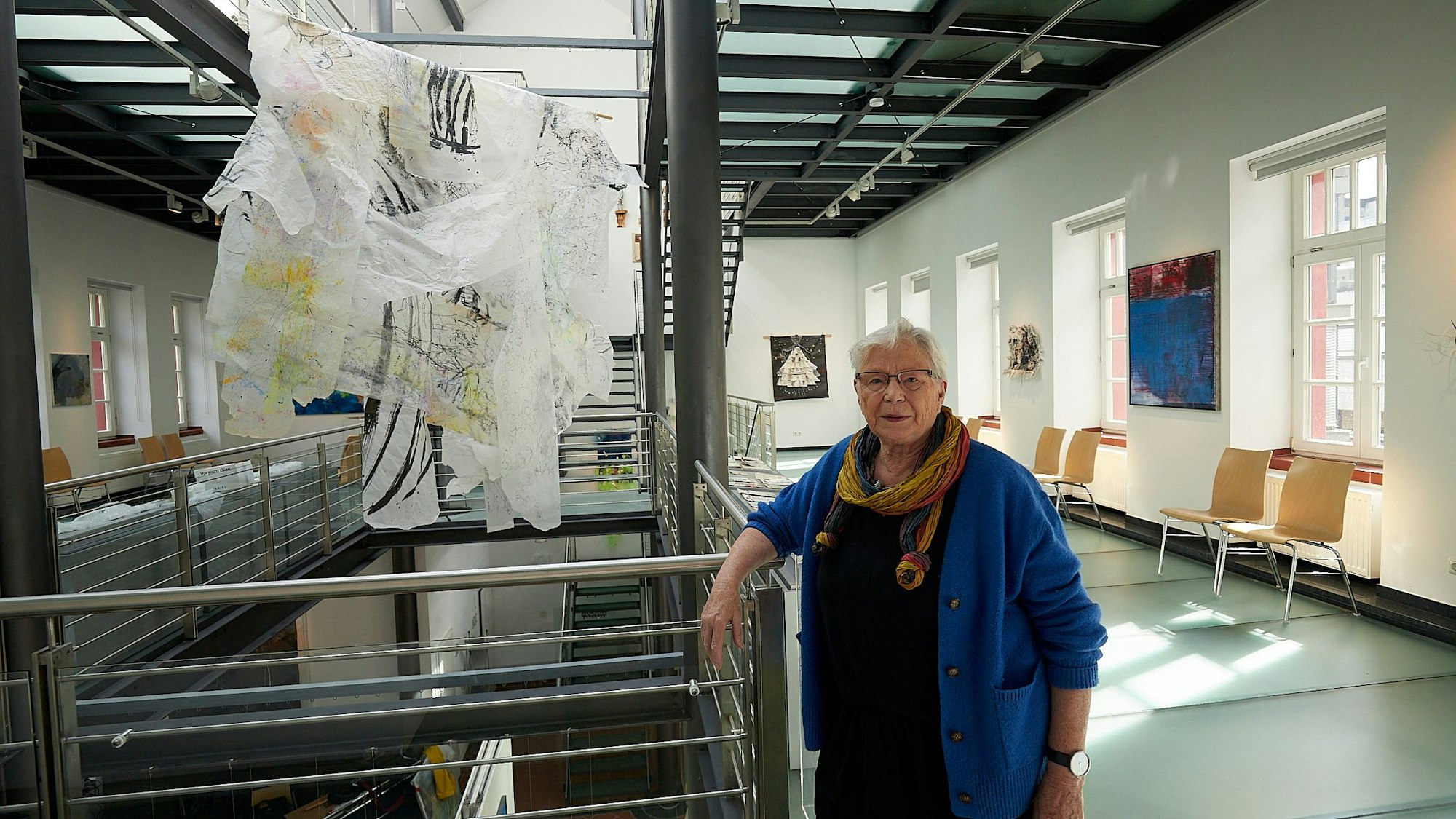 Kuratorin Eva-Maria Hermanns steht im Kunstforum in Gemünd an einer Arbeit von Helga Mols, die im Treppenaufgang installiert ist.