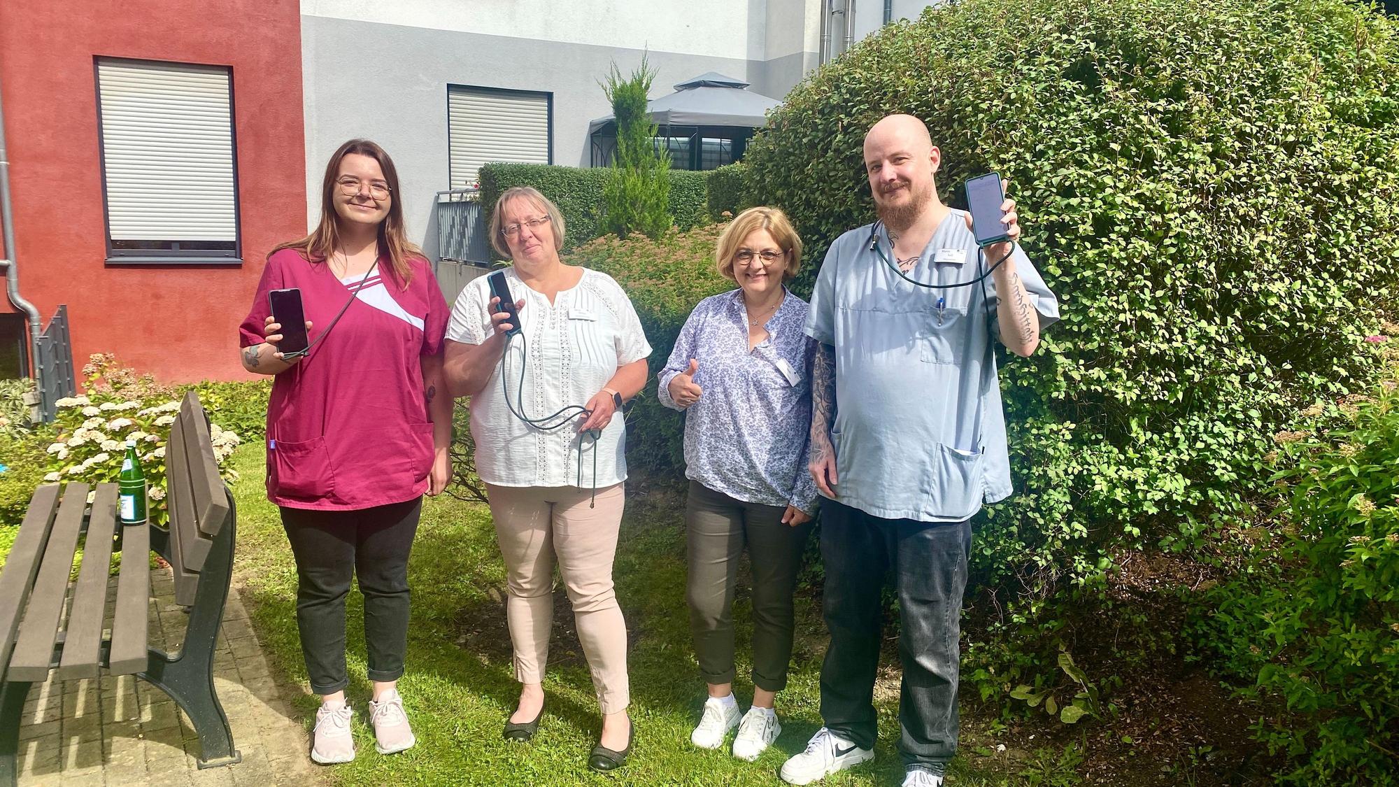 Team Bensberg: Altenpflegerin Mandy Küpper, Pflegedienstleiterin Silvia Mebus, Einrichtungsleiterin Elisabeth Mohr, Altenpfleger Marco Süß halten Handys in der Hand.