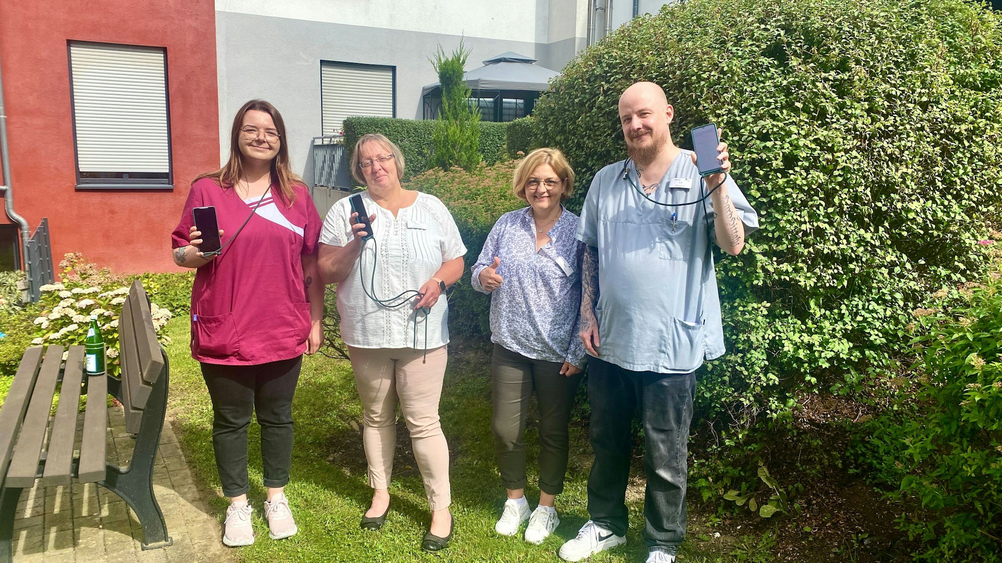 Team Bensberg: Altenpflegerin Mandy Küpper, Pflegedienstleiterin Silvia Mebus, Einrichtungsleiterin Elisabeth Mohr, Altenpfleger Marco Süß halten Handys in der Hand.