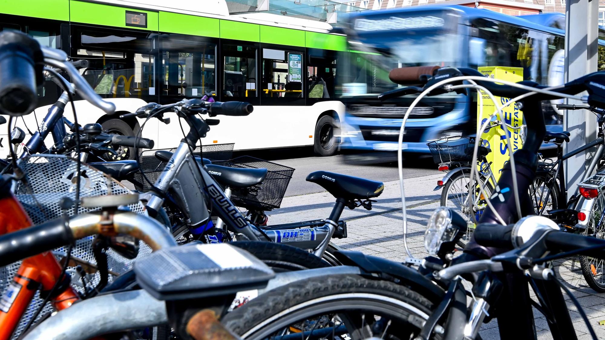 Fahrräder sind am Bahnhof in Euskirchen angekettet, im Hintergrund sind zwei Busse zu sehen.