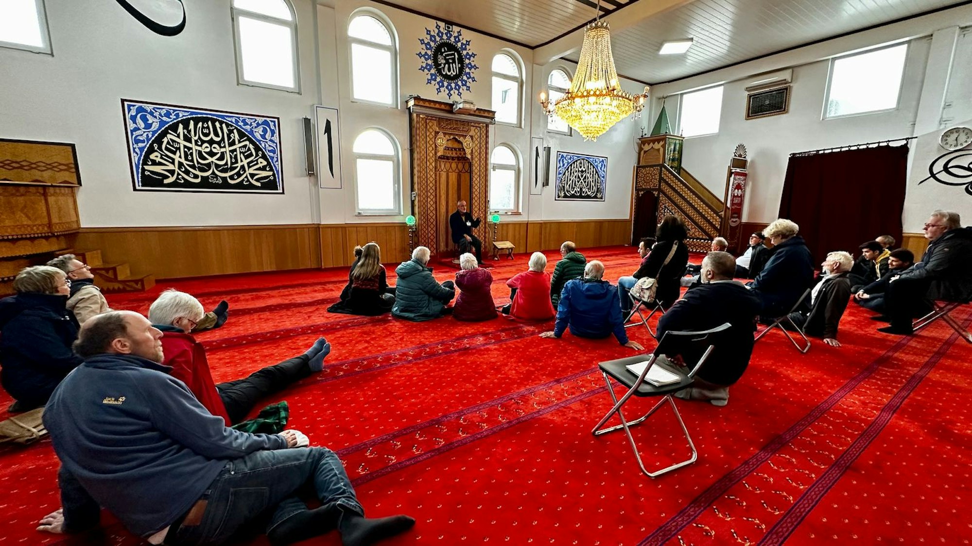Besucher einer Moschee sitzen auf dem Boden