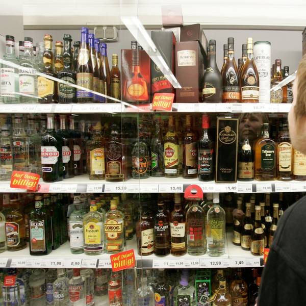 Ein junger Mann steht in einem Supermarkt in Bremen vor einem Spirituosenregal.