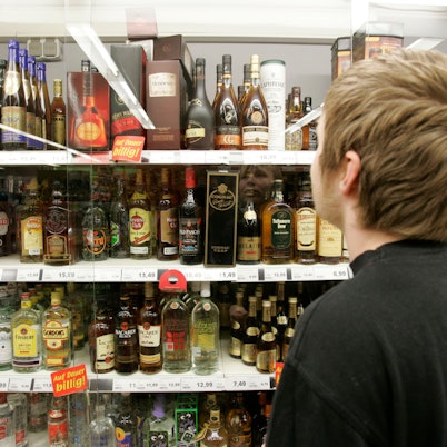 Ein junger Mann steht in einem Supermarkt in Bremen vor einem Spirituosenregal.