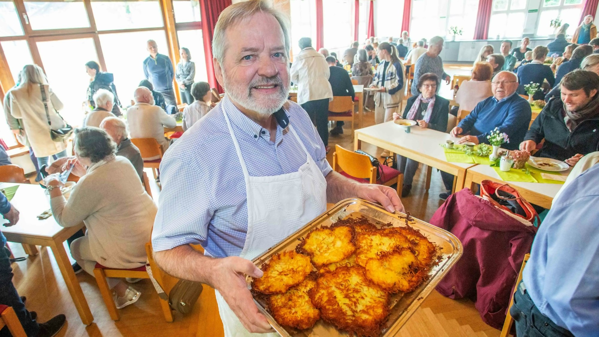 Ein Mann hält ein Tablett mit Reibekuchen in den Händen.