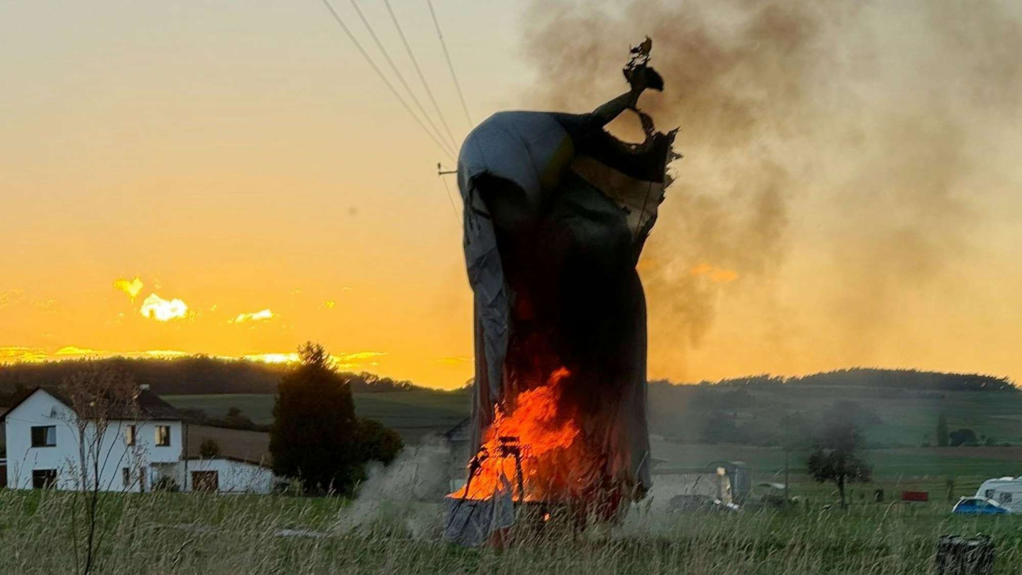Die Hülle eines Heißluftballons hängt bei Zülpich-Schwerfen in einer Stromleitung. Der Korb darunter brennt.