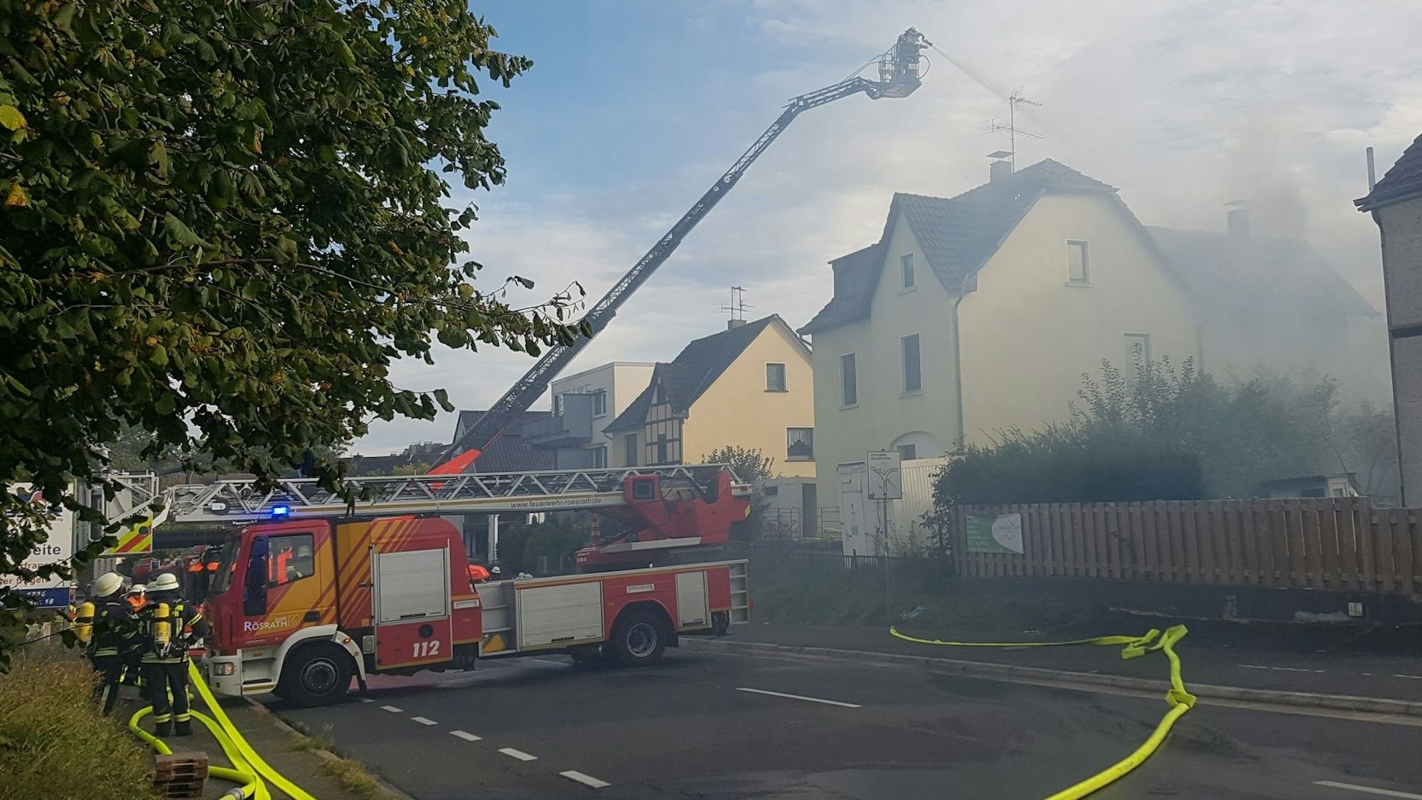 Von einer Drehleiter aus löschen Feuerwehrleute ein brennendes Haus.