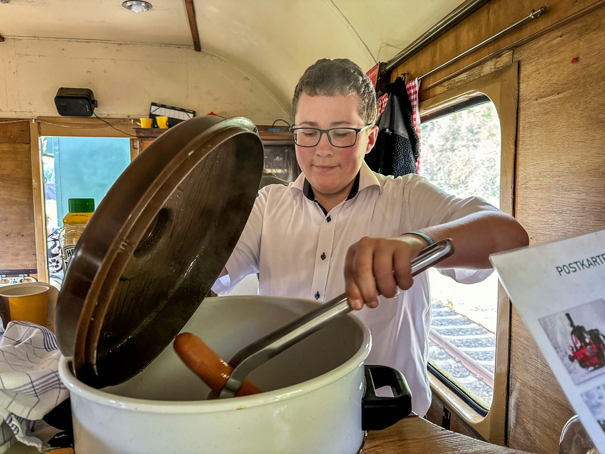 Letzter Fahrtag des Dampfzugs Bergischer Löwe in Oberberg. Die Lkomotive Waldbröl geht in die Winterpause.
Der 14-jährige Marelon Zupke arbeitet im Buffetwagen und holt eine Bockwurst aus dem Kessel.