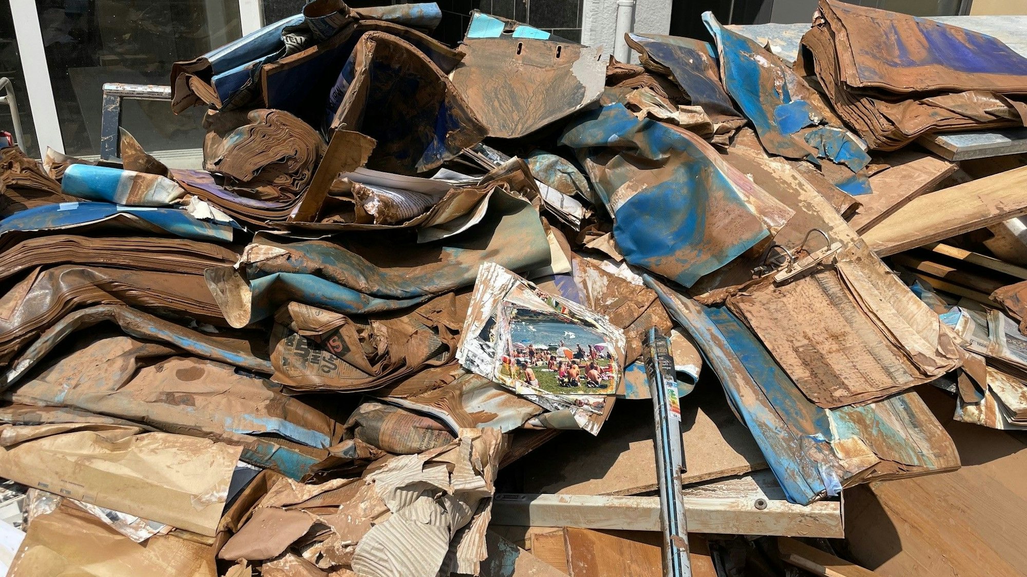 Matschverkrustete, zerstörte Zeitungen liegen auf einem großen Haufen zusammen.