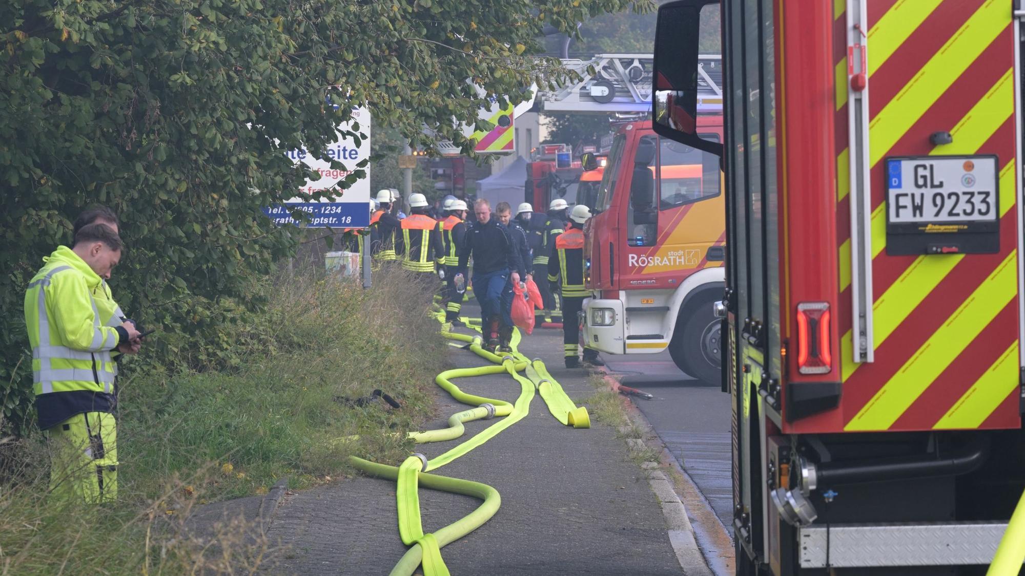 Feuerwehreinsatzfahrzeuge und -leute stehen an der Kölner Straße in Rösrath.