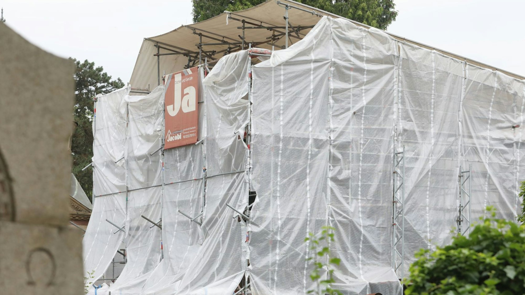 Weiße Planen und Gerüste umgeben ein Gebäude.