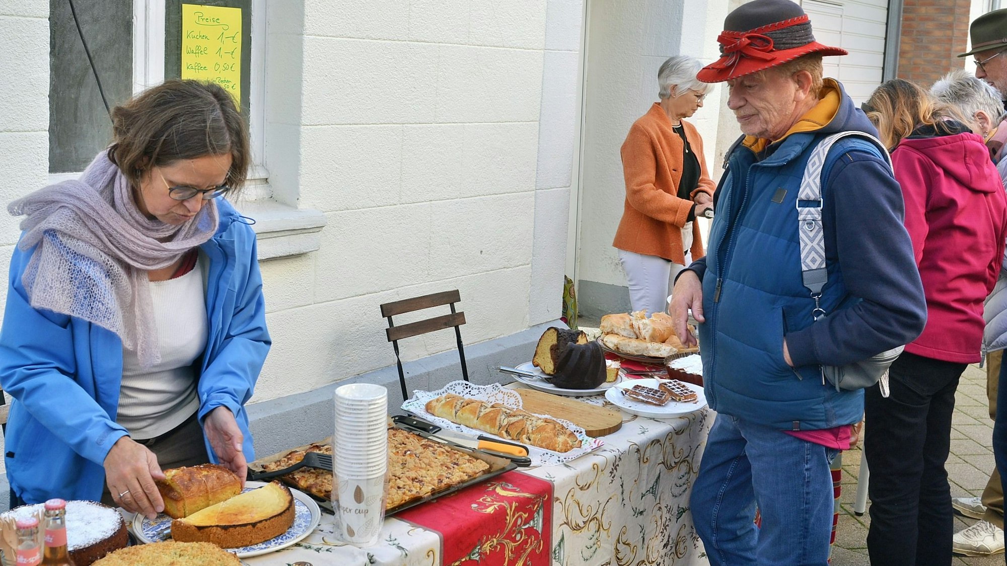 An einem Stand auf der Straße wird Kuchen verkauft, ein Mann steht davor und blickt auf die Kuchen.