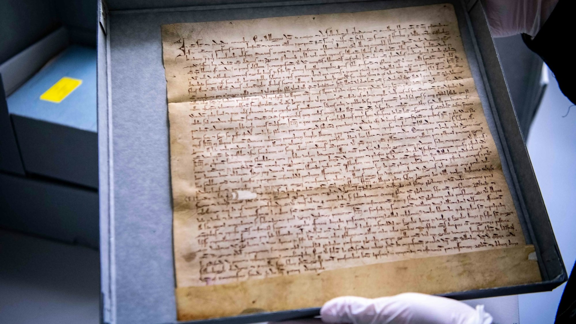 Zwei Hände in weißen Handschuhen halten die originale Stadtrechtsurkunde von Euskirchen.