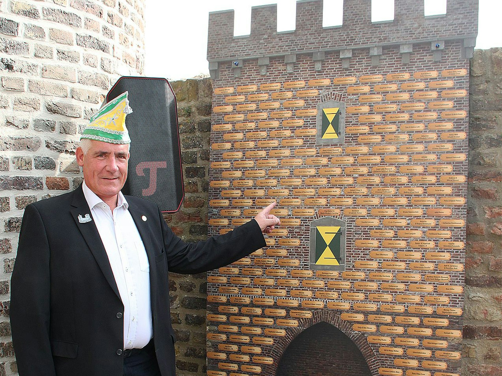 Ein Karnevalist mit Narrenkappe steht vor einem kleineren Nachbau des Weiertors aus Pappe. Darauf zu sehen sind zahlreiche Schildchen mit den Namen aller bisherigen Spender.