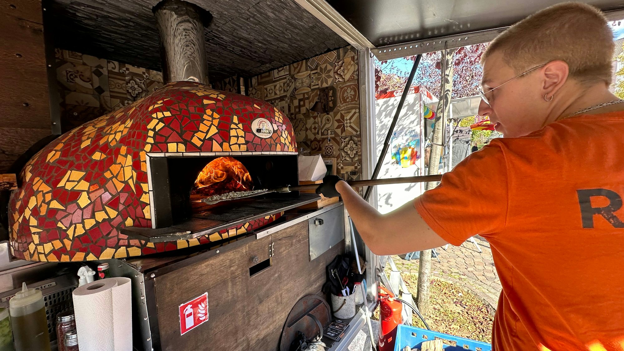 Leon Dettenberg schiebt die Pizza in den Holzofen.