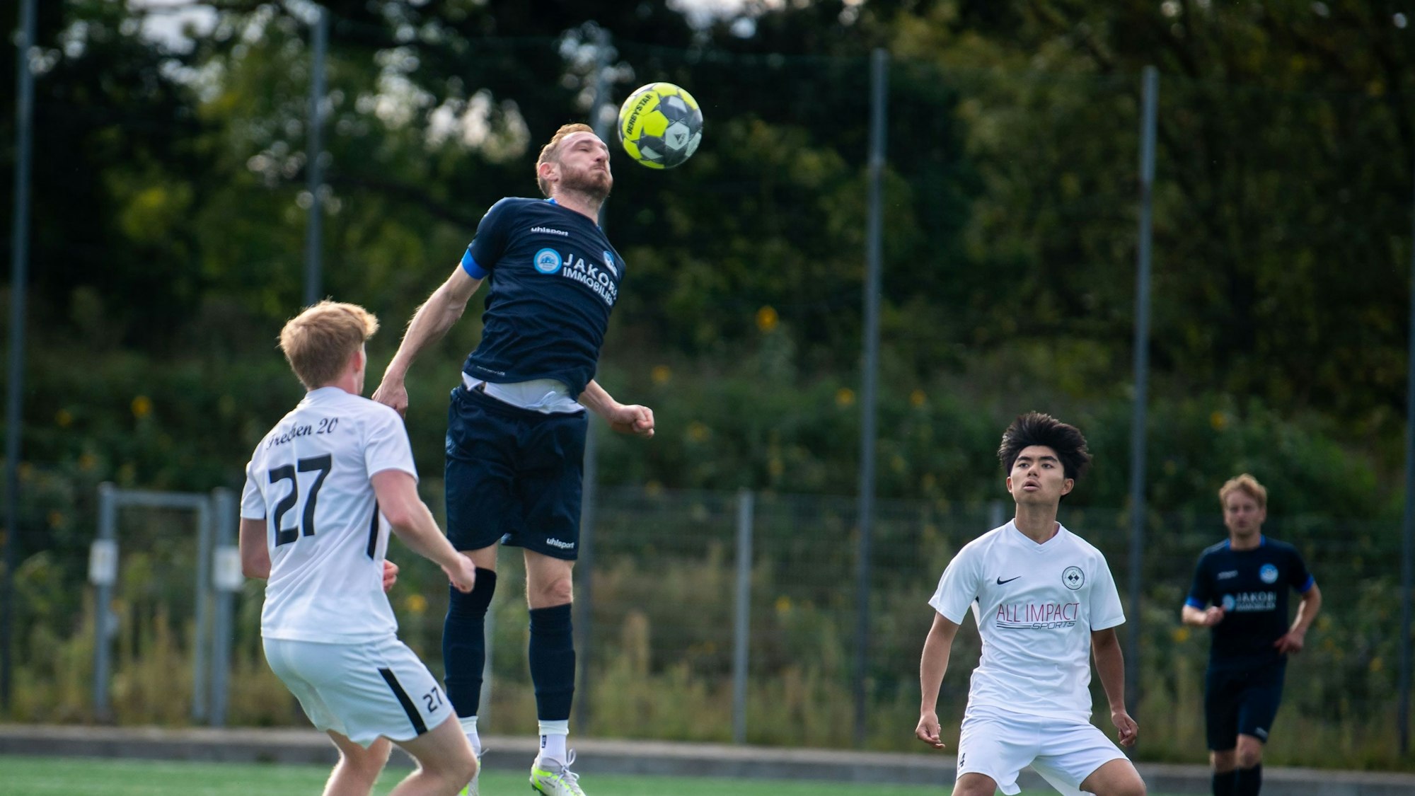 Zwei Gegenspieler schauen zu, wie Moritz Hartmann, der hochgesprungen ist, den Ball weiterleitet.
