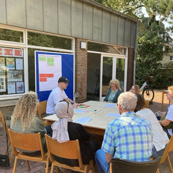 Menschen sitzen an einem Tisch zusammen