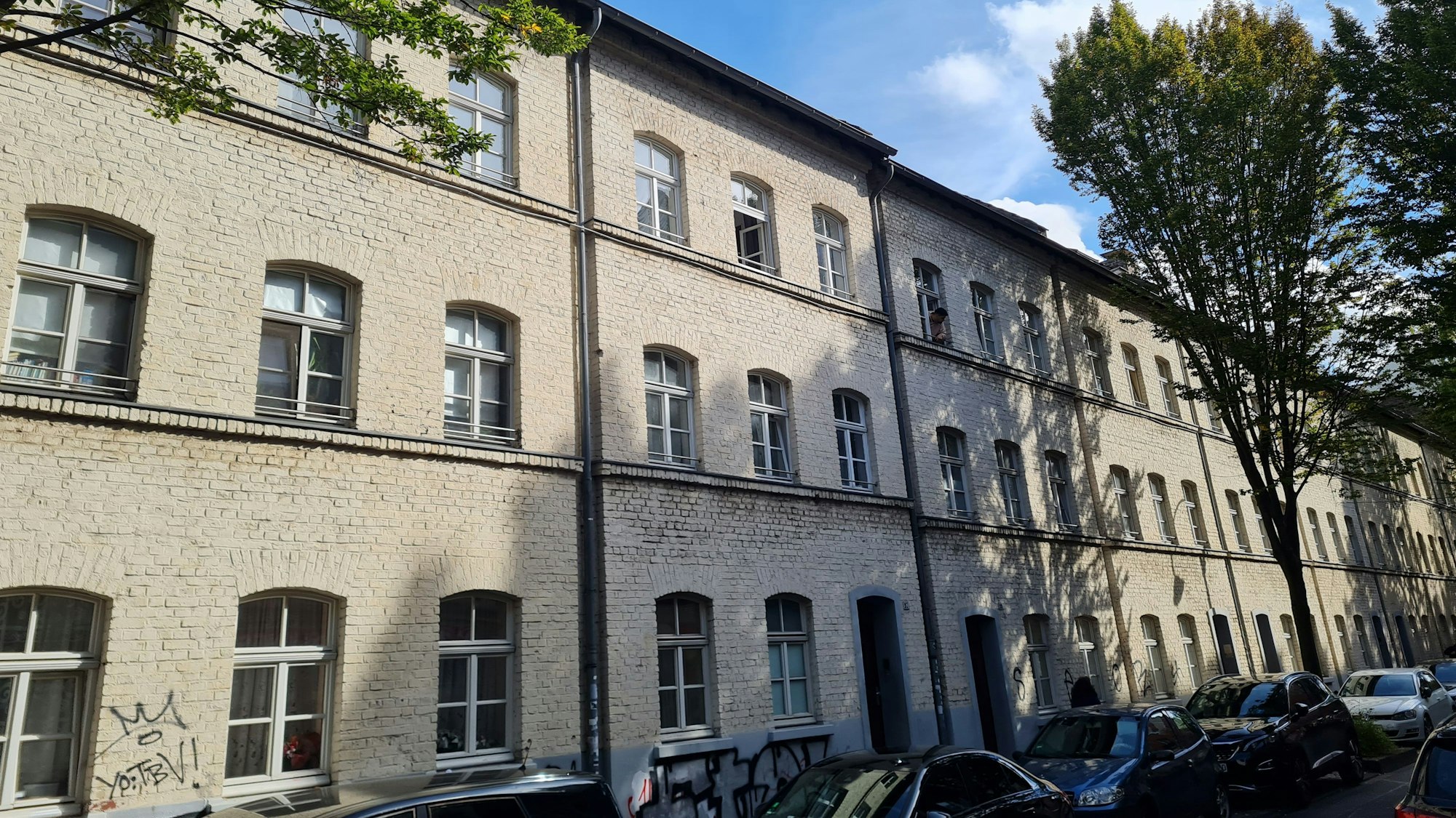 Gleichförmige helle dreigeschossige Backsteinhäuser säumen eine Straße.