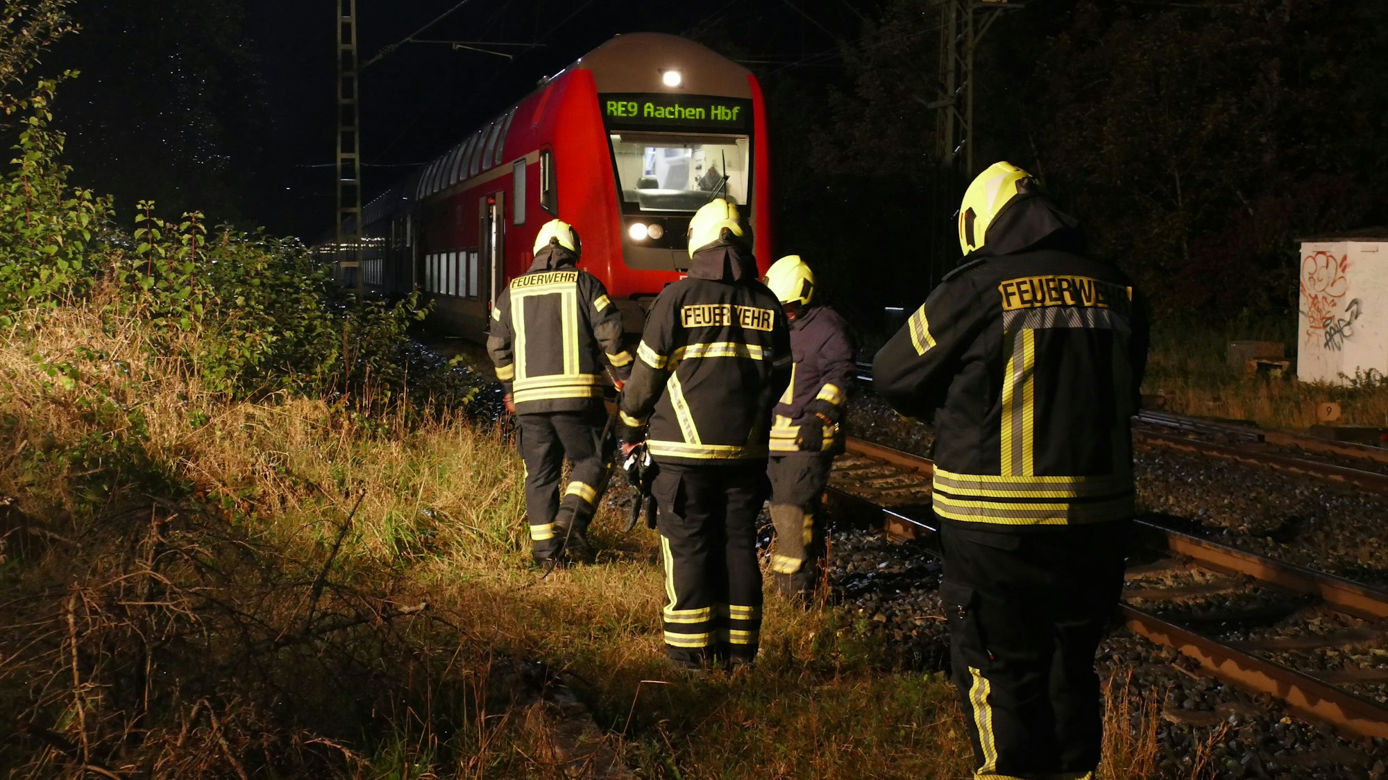 Feuerwehrleute stehen vor dem havarierten Zug am Gleis.